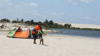 Papa steht mit Sohn am Strand und startet einen Kite