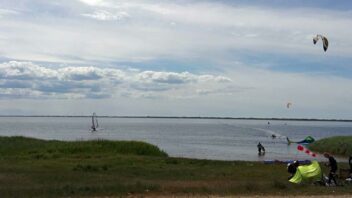 Blick auf das Meer mit Kitesurfern am Strand und im Wasser